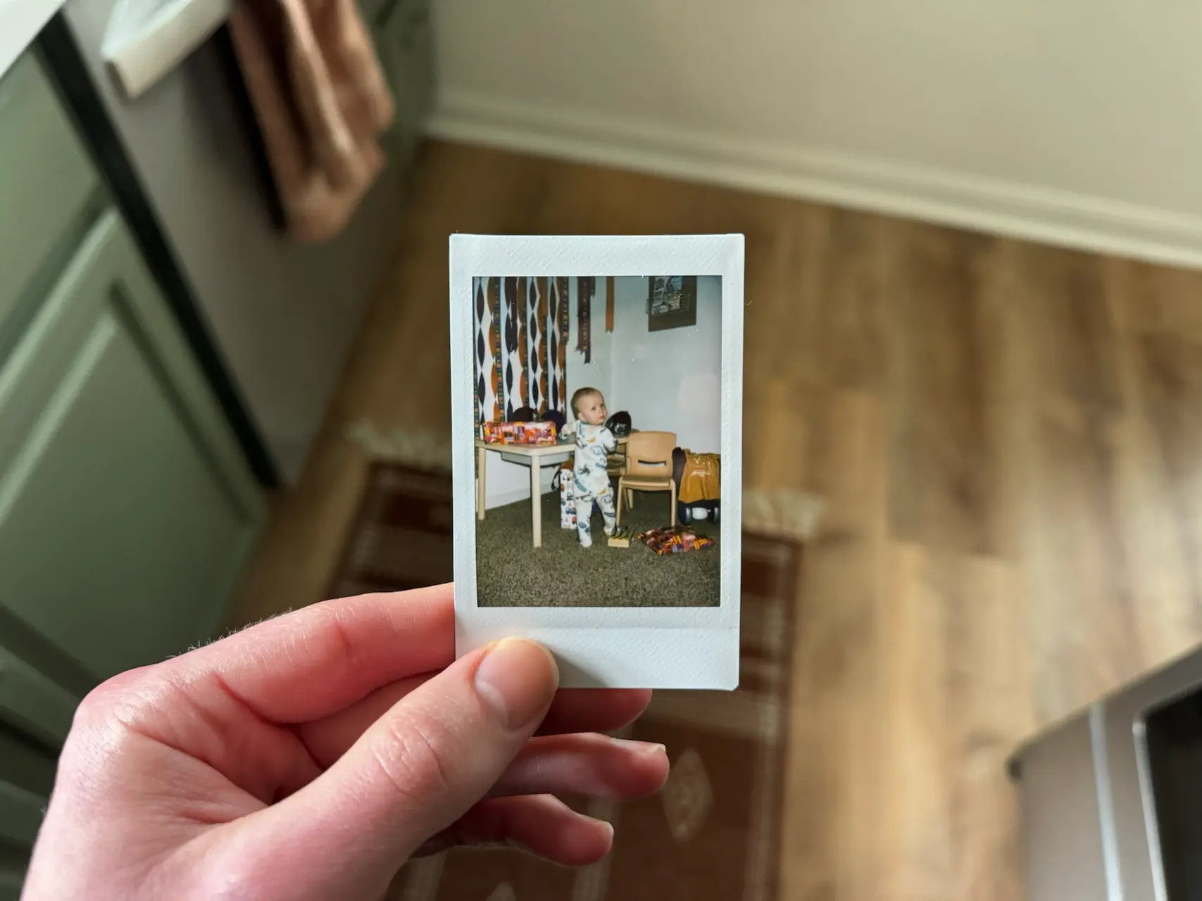 Holding a polaroid photo of micah in front of a table with presents